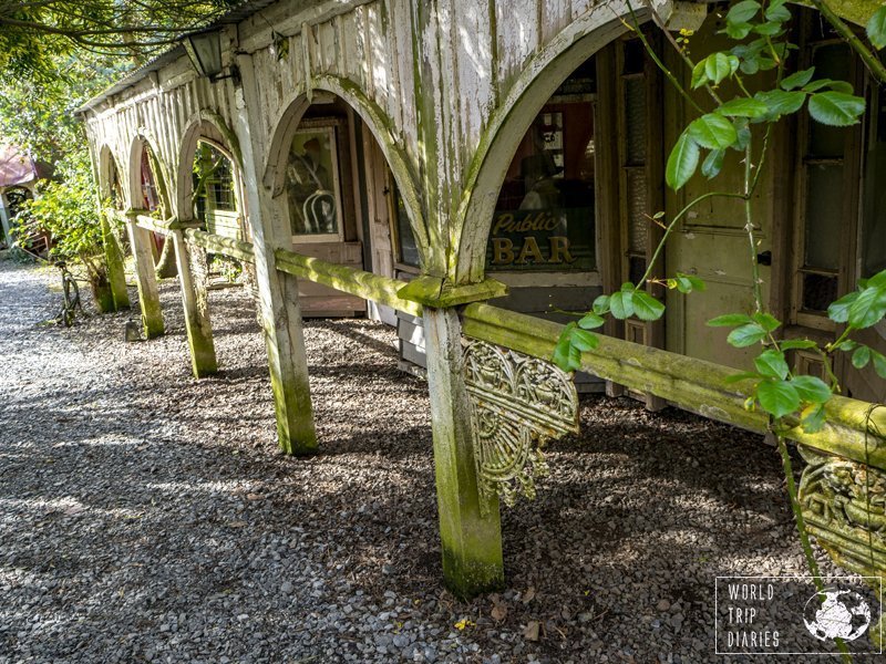 The wooden arches of a veranda, with plants dangling from them at Demolition World, NZ.