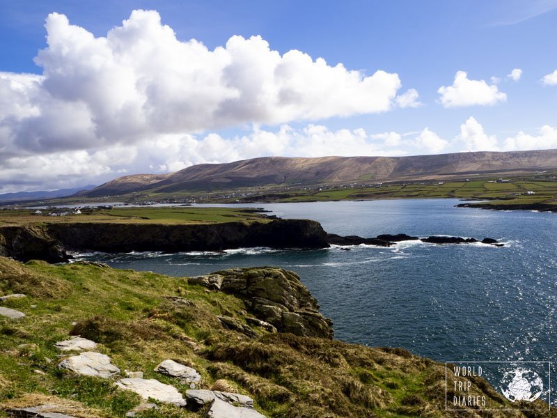 Green grass in the foreground, the sea and a cliff in the middle, mountains and blue skies at the back. Ireland at its prettiest. Click for more!