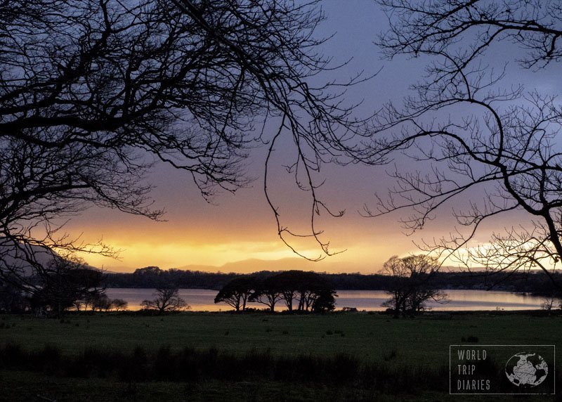 A sunset on the back, reflecting on the lake and trees in the front. That's Lake Muckross, in Ireland, and its stunning sunsets. Click for more!